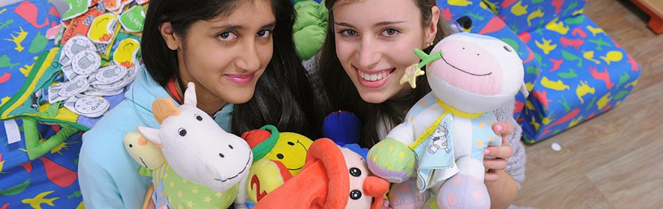 Early years students holding up soft toys